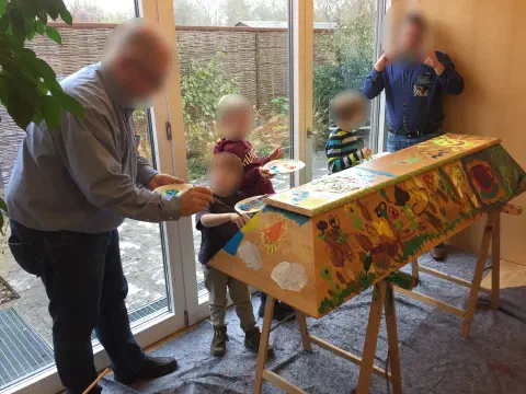 Familie bemalt gemeinsam das Kopfende des Sarges