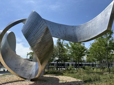 Metallskulptur mit eingravierten physikalischen Formeln vor dem CERN-Gelände
